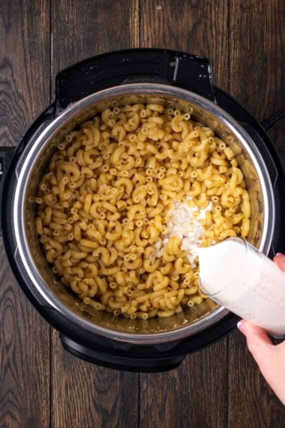 Half and half being added to cooked macaroni inside the Instant Pot.