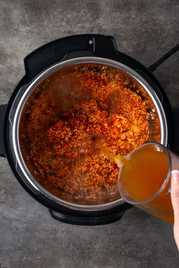 Broth poured over Mexican rice inside the Instant Pot.