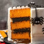 Side view of a spider cake with a large slice cut out, revealing the orange cake layers inside.