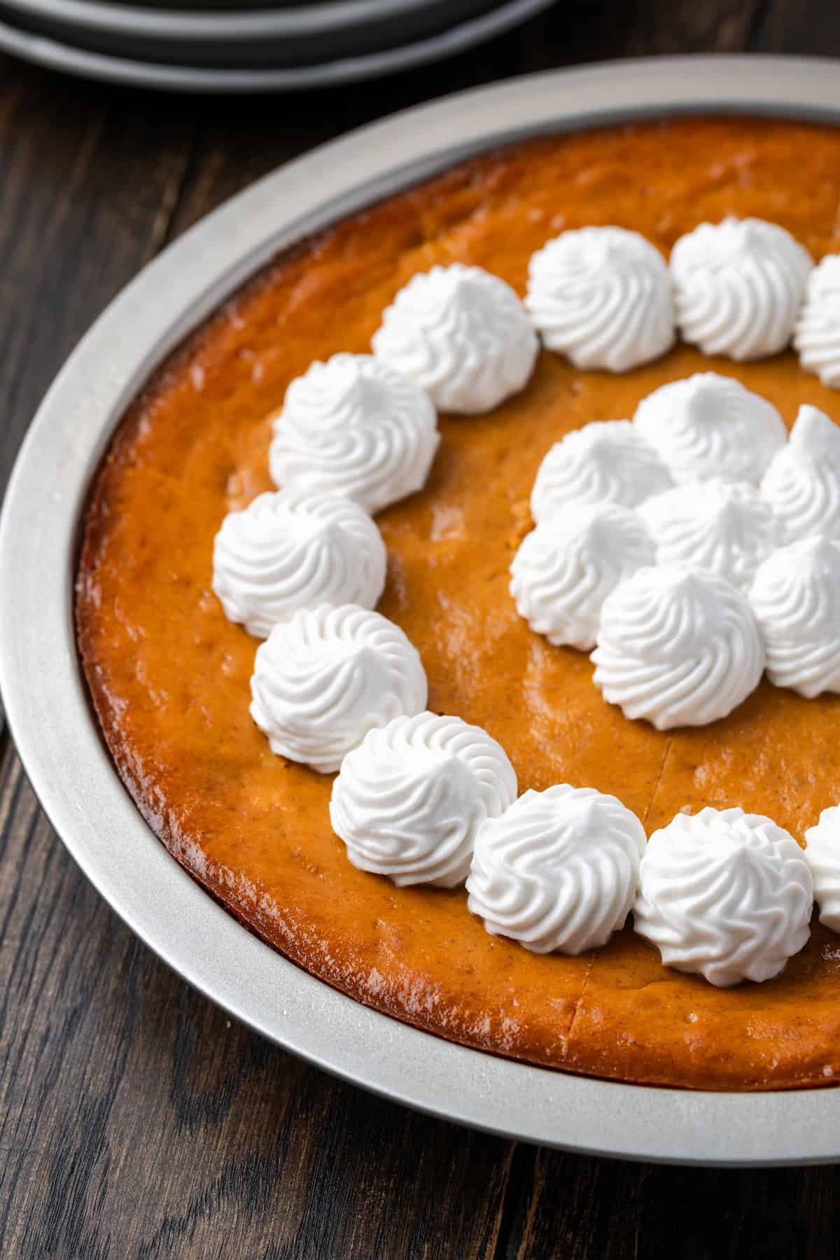 Crustless pumpkin pie in a pie plate topped with whipped cream.