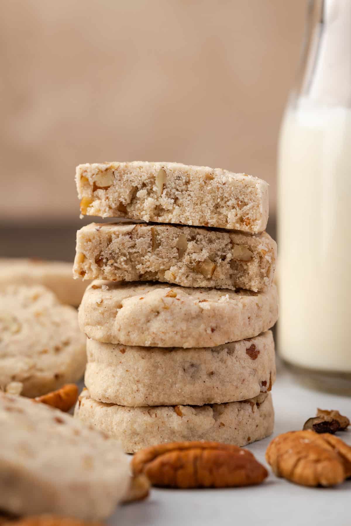 A stack of pecan sandies with the top cookie broken in half.