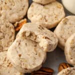 Close up of assorted pecan sandies, one propped against another cookie with a bite missing.