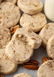 Close up of assorted pecan sandies, one propped against another cookie with a bite missing.