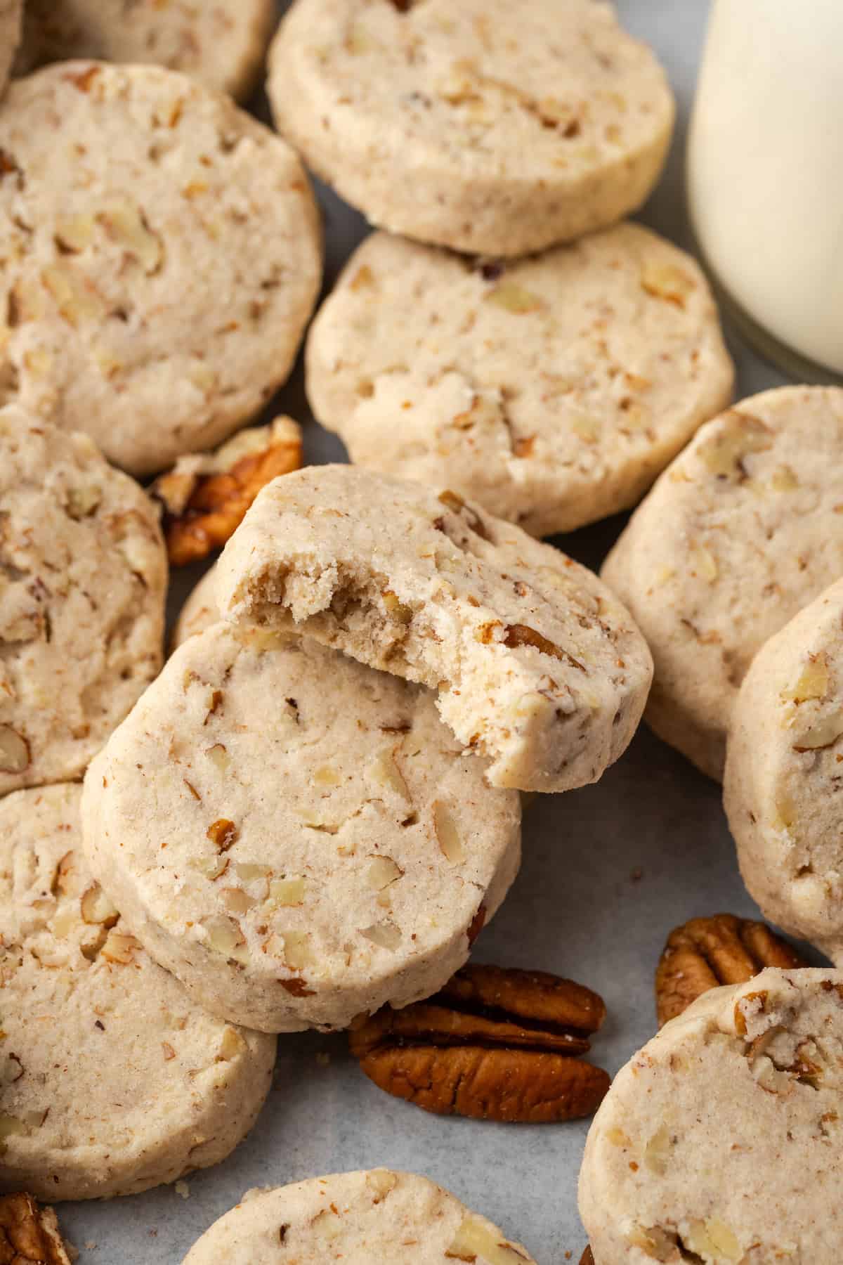 Close up of assorted pecan sandies, one propped against another cookie with a bite missing.