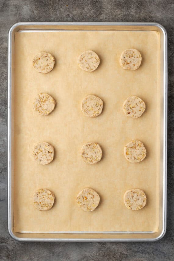 Rows of pecan sandies cookies on a parchment-lined baking sheet.