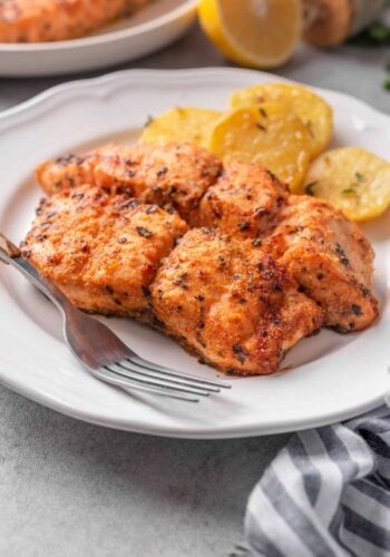 Cooked air fryer salmon on a plate with a fork.