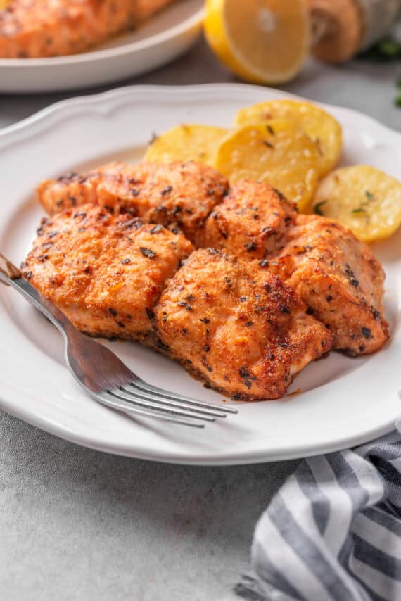 Cooked air fryer salmon on a plate with a fork.