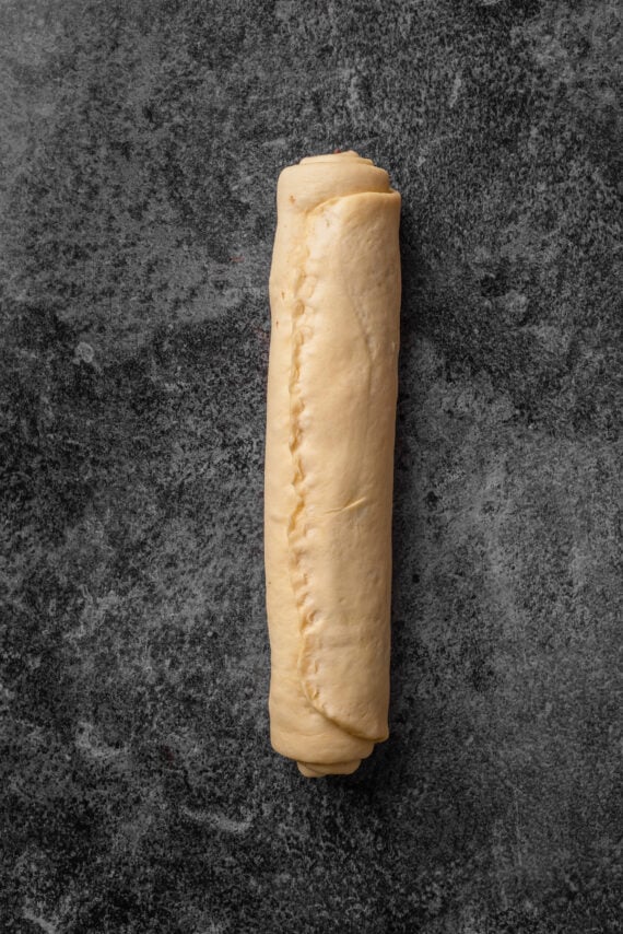 A rolled chocolate babka dough log on a countertop.