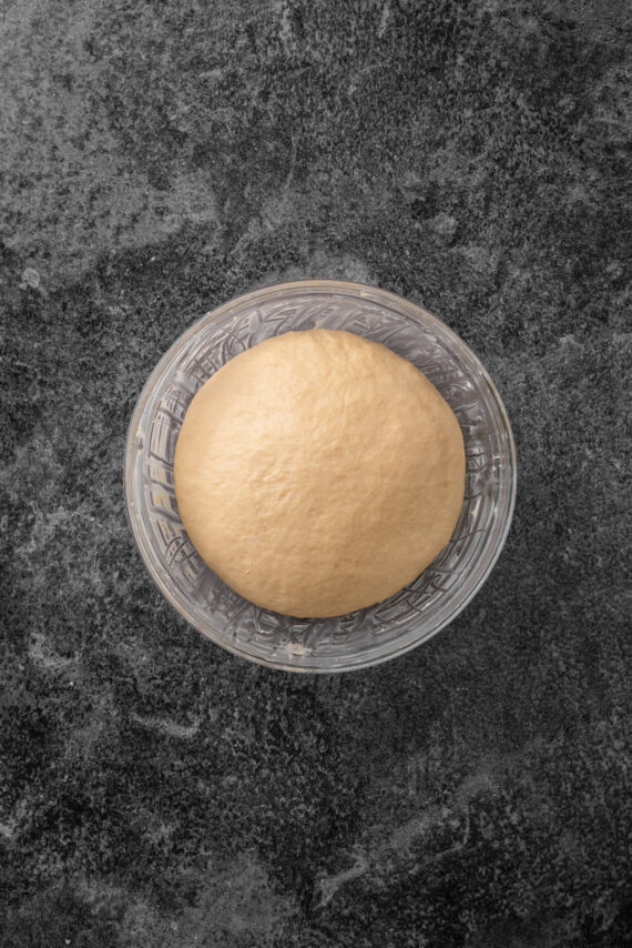 Overhead view of babka dough in a large glass bowl.