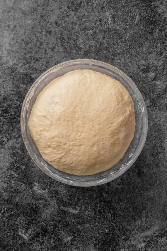 Overhead view of risen dough in a large glass bowl.