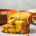 Two halves of an air fryer grilled cheese stacked with gooey cheese dripping out from the bread slices.