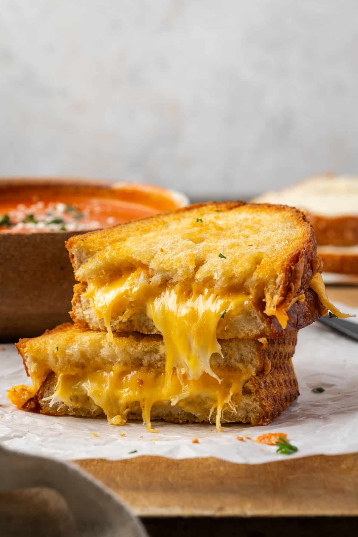 Two halves of an air fryer grilled cheese stacked with gooey cheese dripping out from the bread slices.