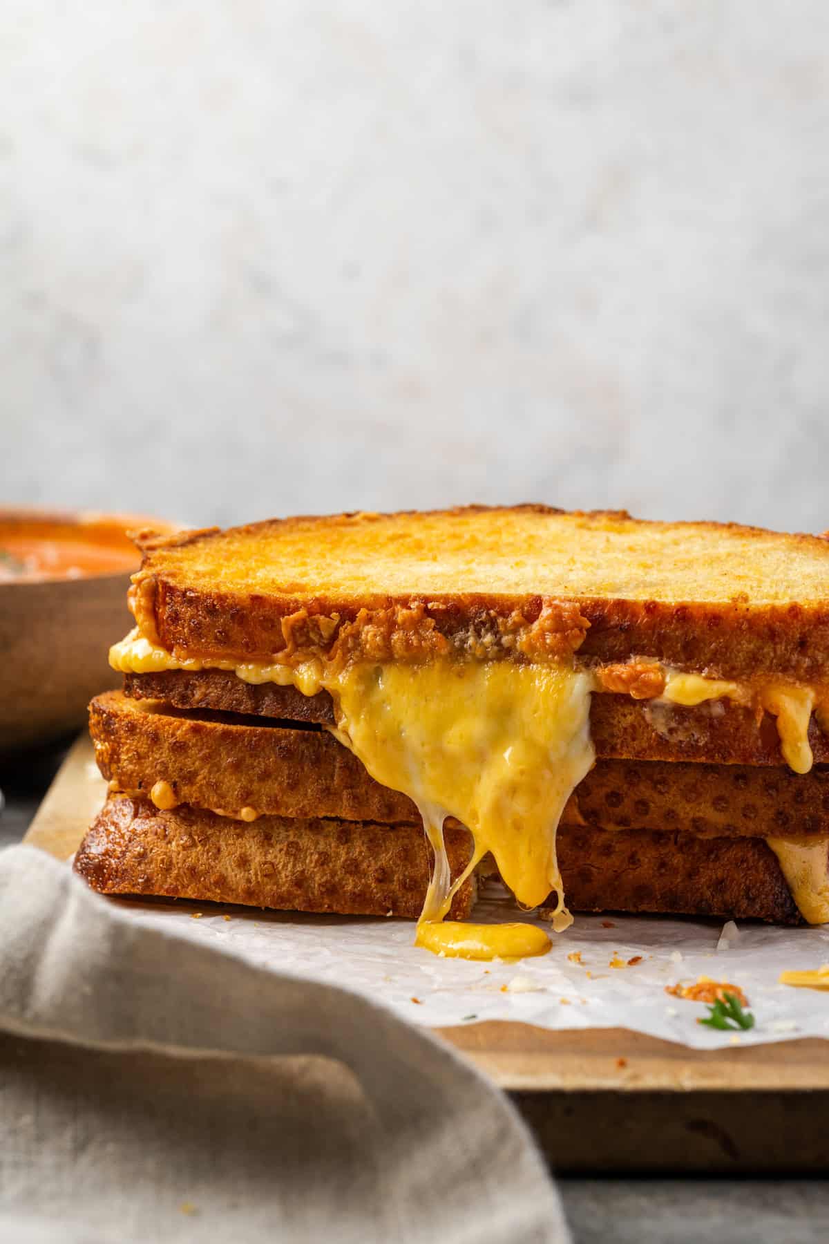 Two air fryer grilled cheese sandwiched stacked on top of one another, with gooey cheese escaping from the side.