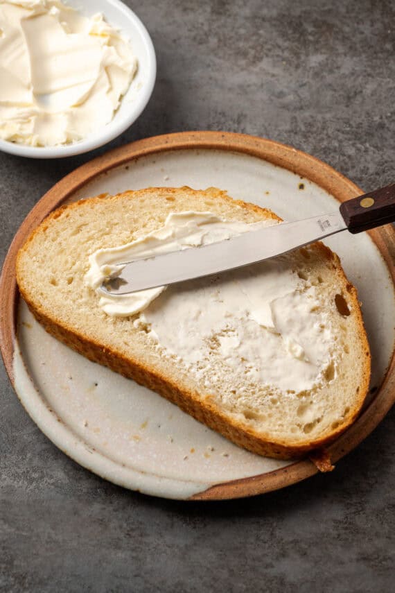 A knife spreading butter over a slice of bread.