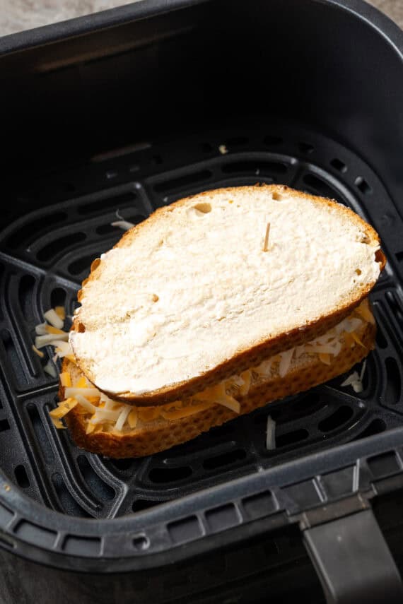 An assembled grilled cheese sandwich inside the air fryer basket.