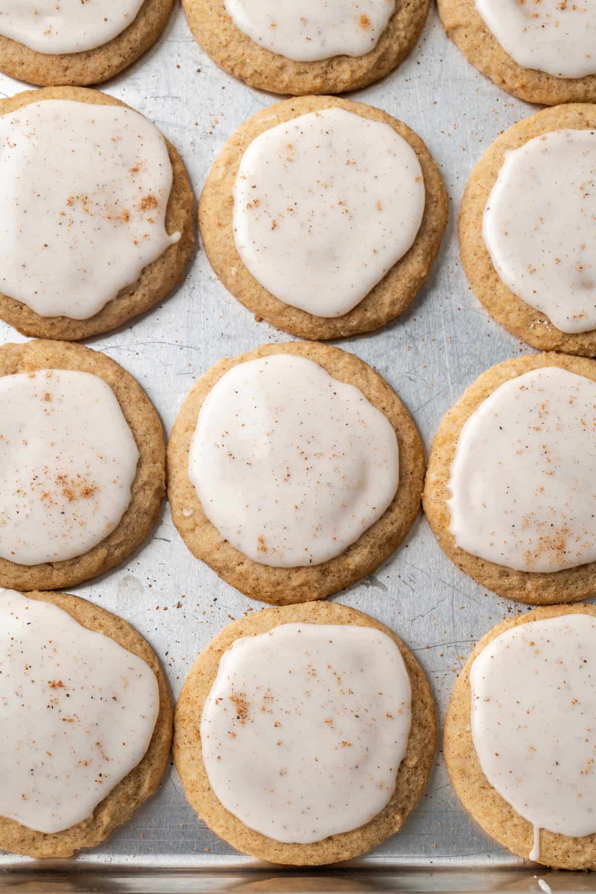 Overhead view of rows of frosted chai sugar cookies on a baking sheet.