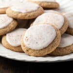 Frosted chai sugar cookies piled on a white scalloped platter.