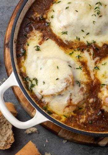 Overhead view of French onion chicken covered with melted cheese in a skillet.