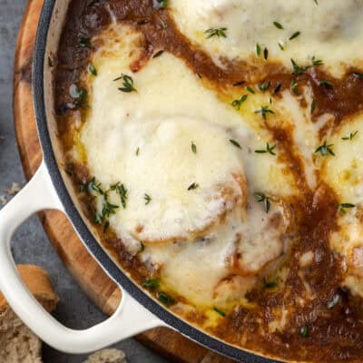 Overhead view of French onion chicken covered with melted cheese in a skillet.