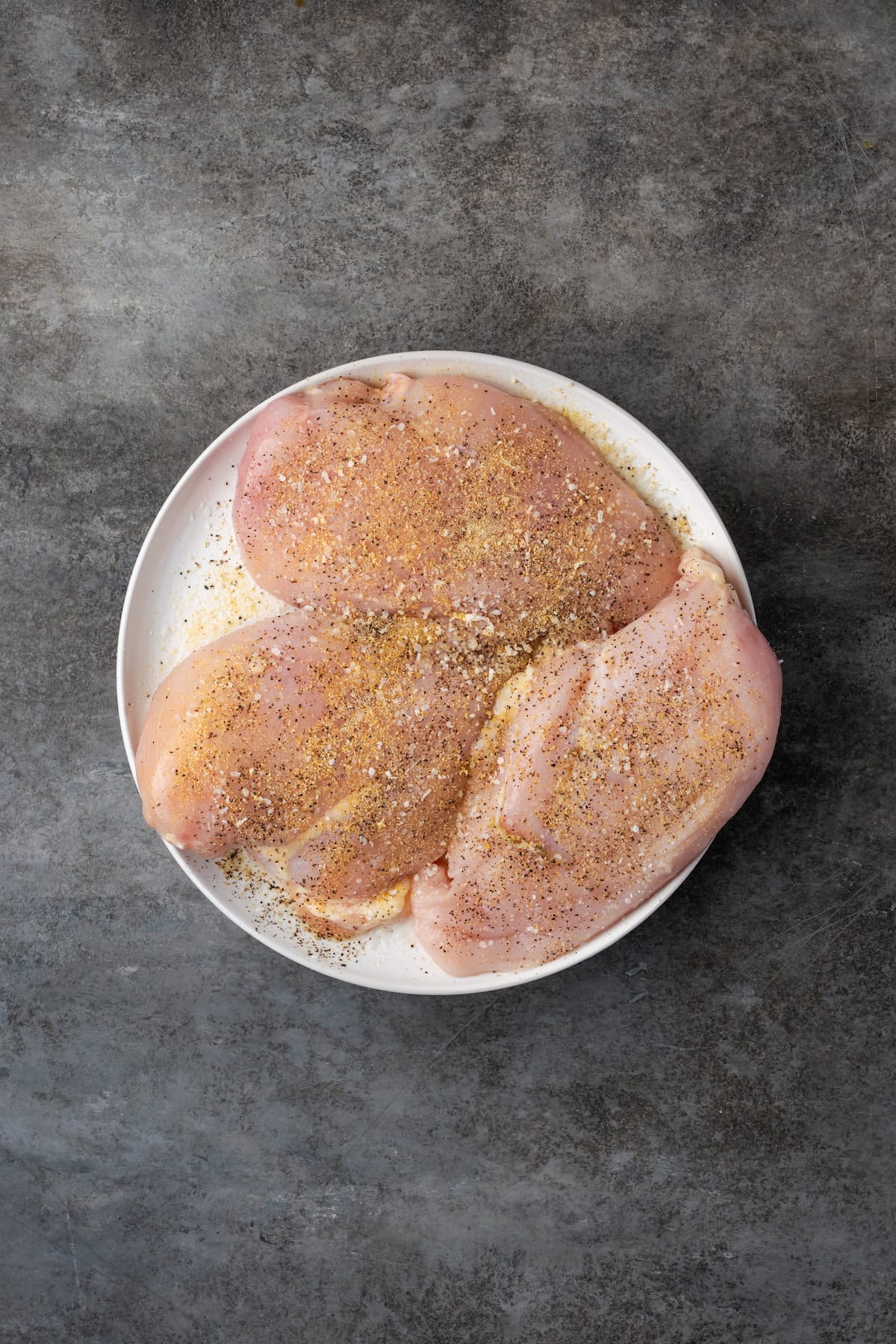 Seasoned chicken breasts on a plate.