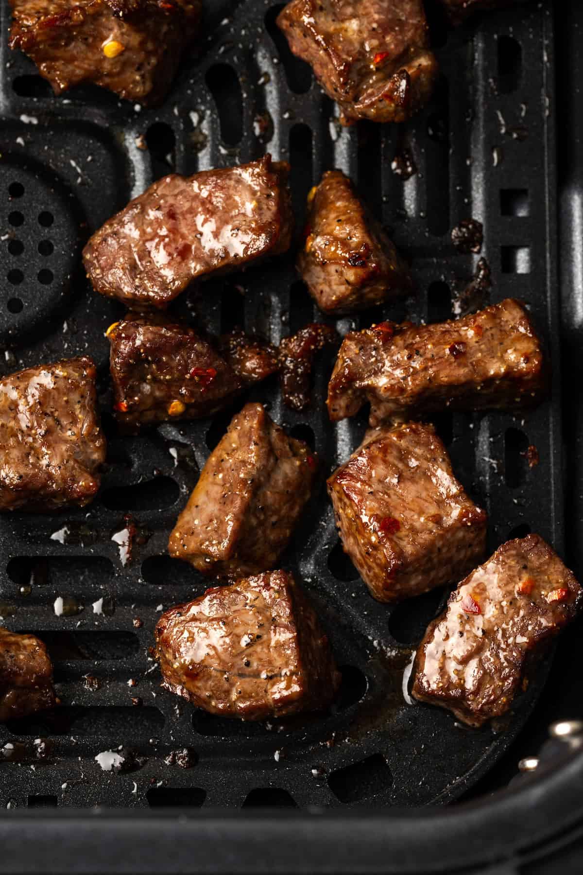 Close up overhead view of air fryer steak bites inside the air fryer basket.