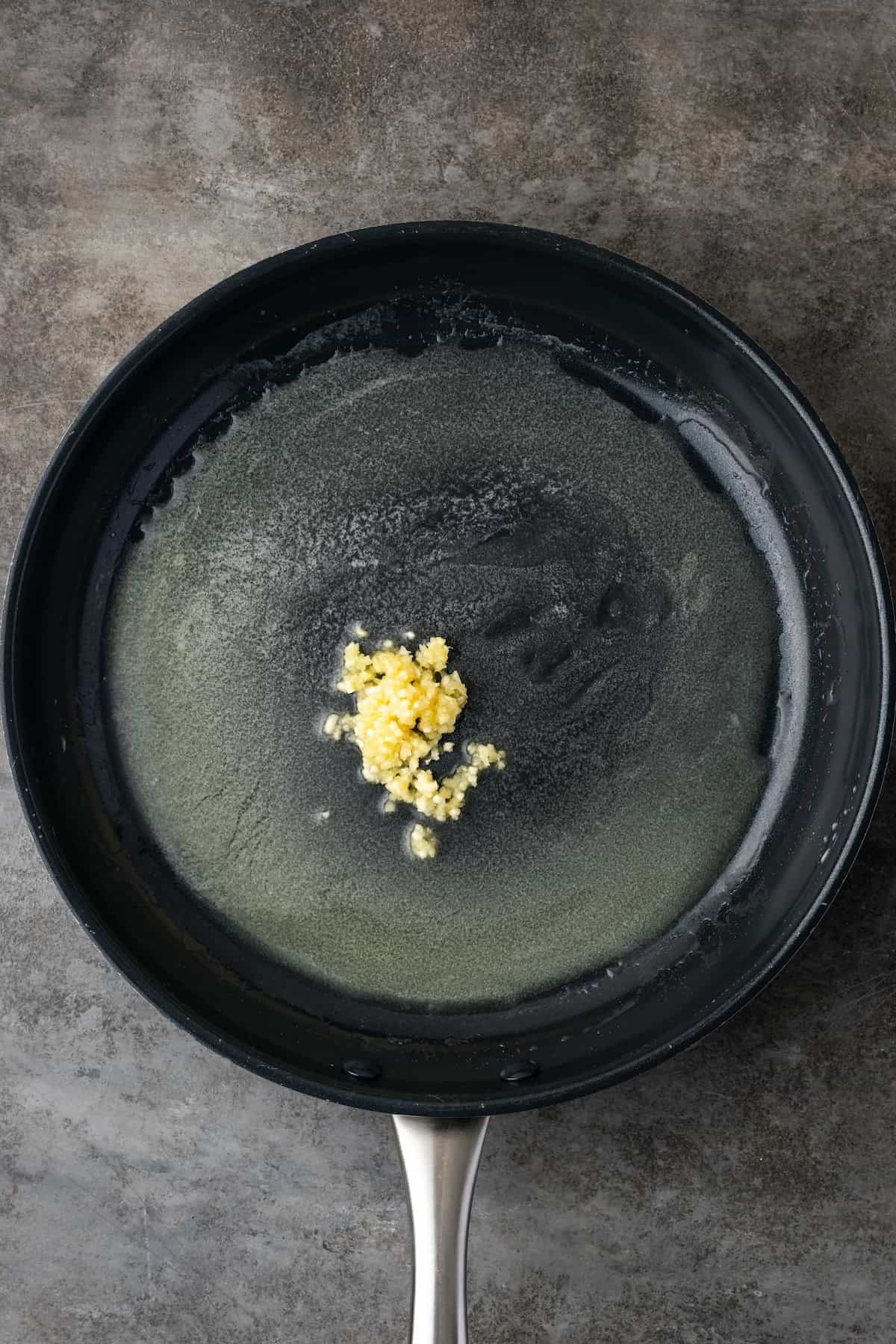 Minced garlic added to melted butter in a skillet.