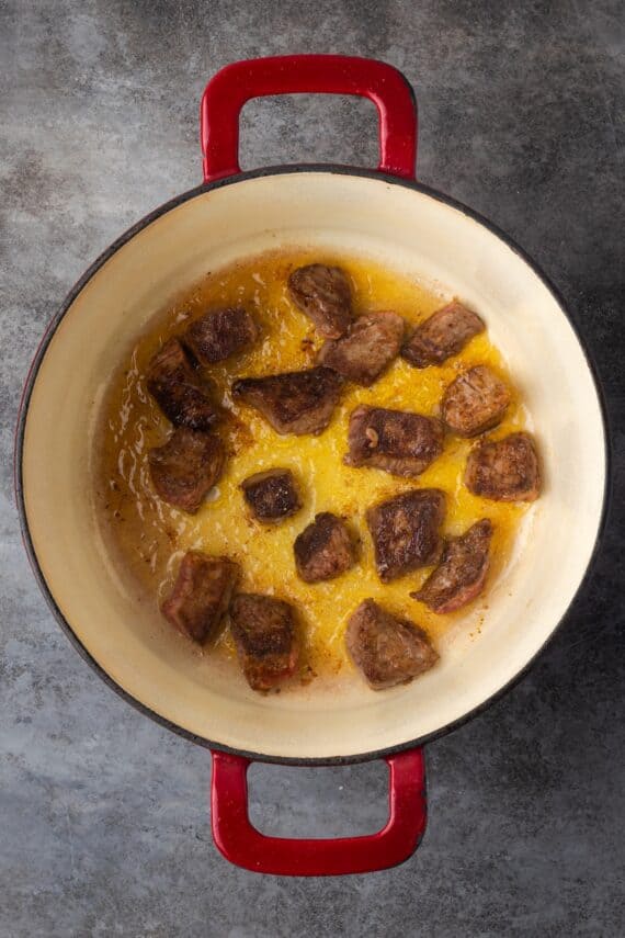 Seared beef chunks in a large pot.