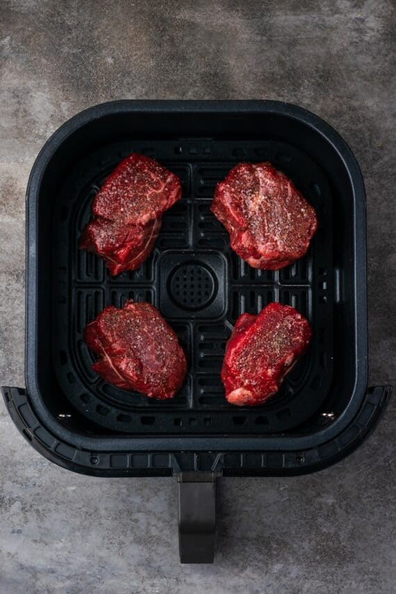 Make juicy, restaurant-quality air fryer filet mignon slathered with homemade garlic compound butter for the ultimate steak dinner! Four seasoned filet mignon steaks inside the air fryer.