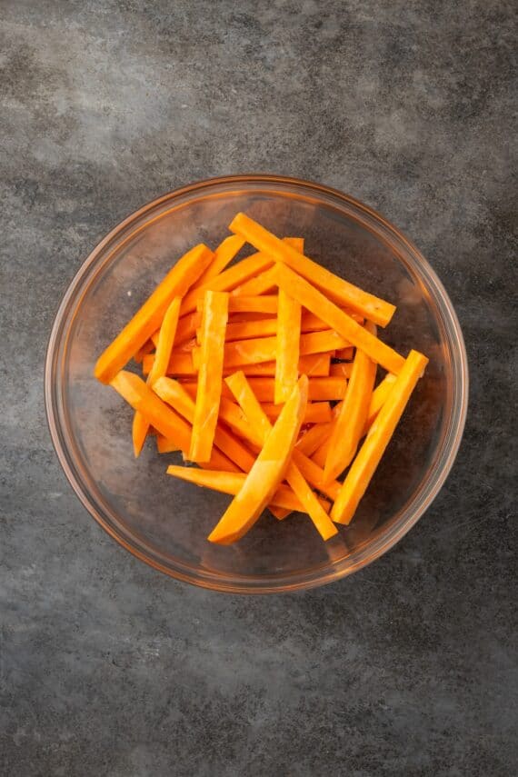 Seasoned with garlic and paprika, crispy air fryer sweet potato fries are tasty and easy to make. It's quicker and lighter than deep frying! Sweet potato fries in a glass bowl.