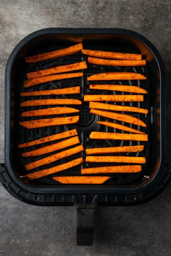 Seasoned with garlic and paprika, crispy air fryer sweet potato fries are tasty and easy to make. It's quicker and lighter than deep frying! Seasoned sweet potato fries arranged in rows inside the air fryer basket.