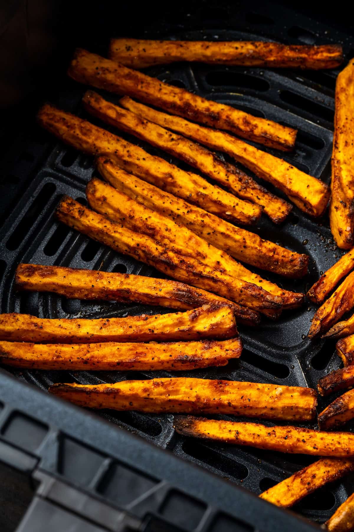 Seasoned with garlic and paprika, crispy air fryer sweet potato fries are tasty and easy to make. It's quicker and lighter than deep frying! Close up of sweet potato fries inside the air fryer basket.