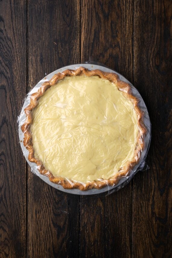This banana cream pie recipe is a classic dessert with a rich vanilla custard layered with heaps of whipped cream and sweet banana slices. Overhead view of banana cream pie in a pie plate.