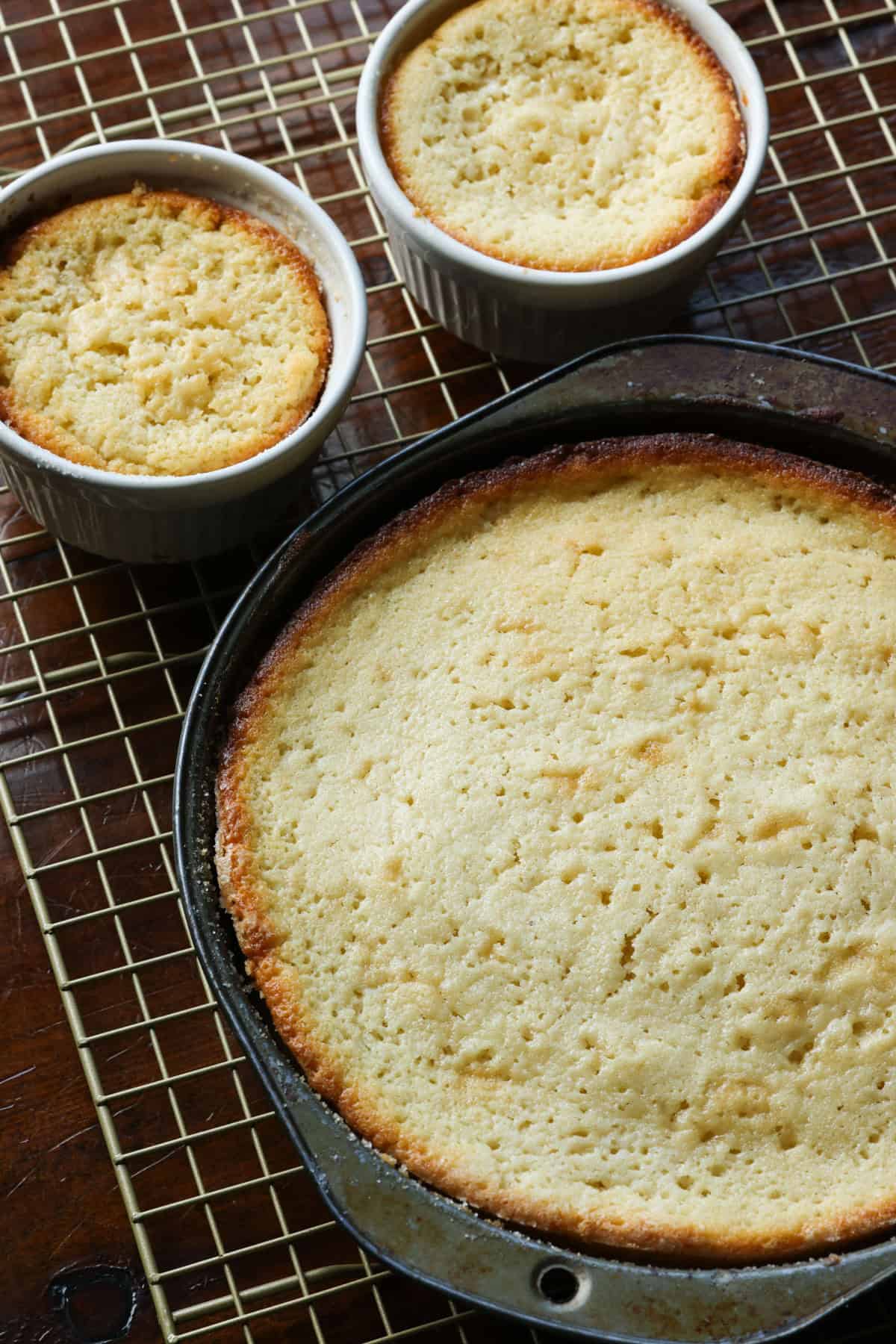 This insanely moist Copycat Butter Cake Recipe is a dupe for the Crumbl Butter Cake and the warm butter cake at California Pizza Kitchen. Butter cake baked in a 9- inch round cake pan and also in single serve ramekins cooling on a wire rack.