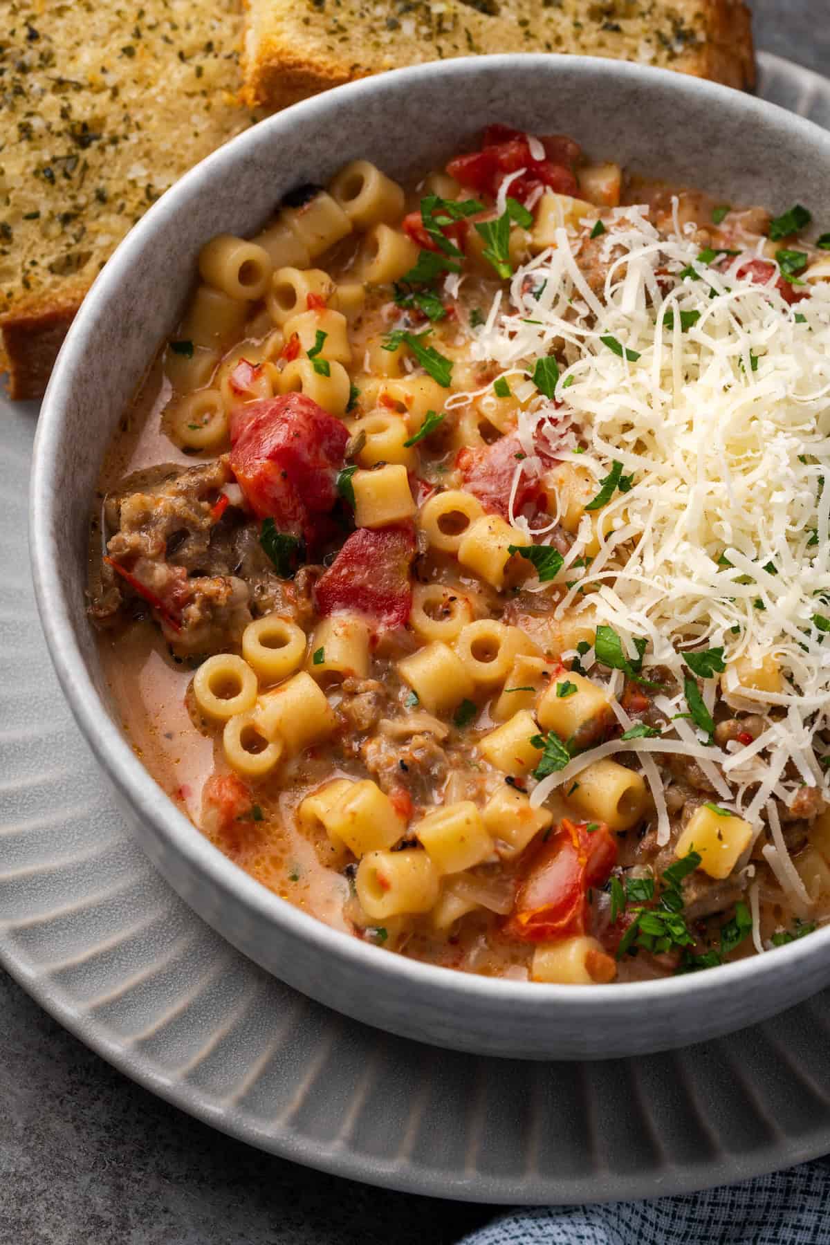 Overhead view of creamy Italian sausage soup in a bowl garnished with grated parmesan cheese.