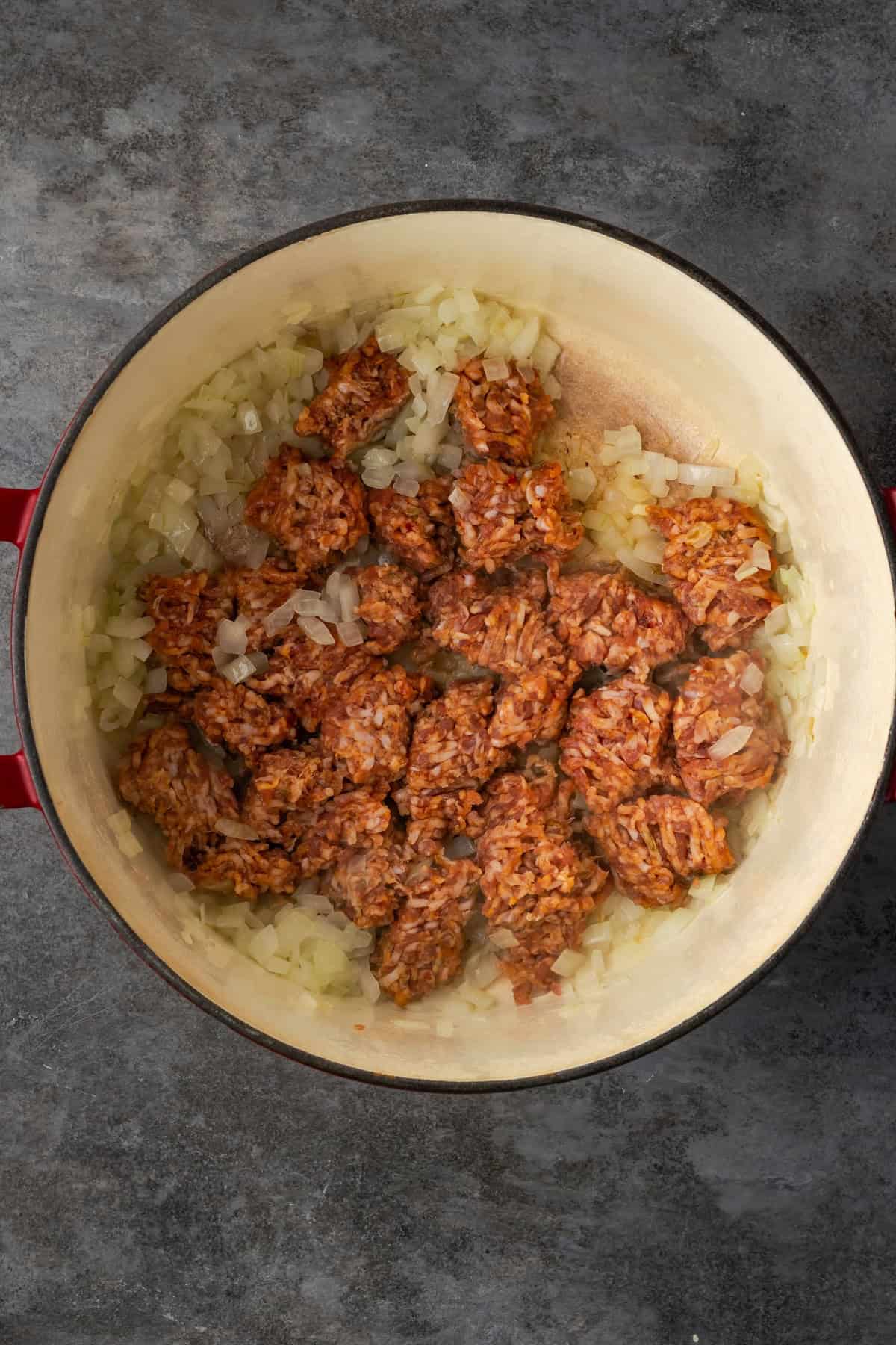 Italian sausage added to sautéed onions in a Dutch oven.