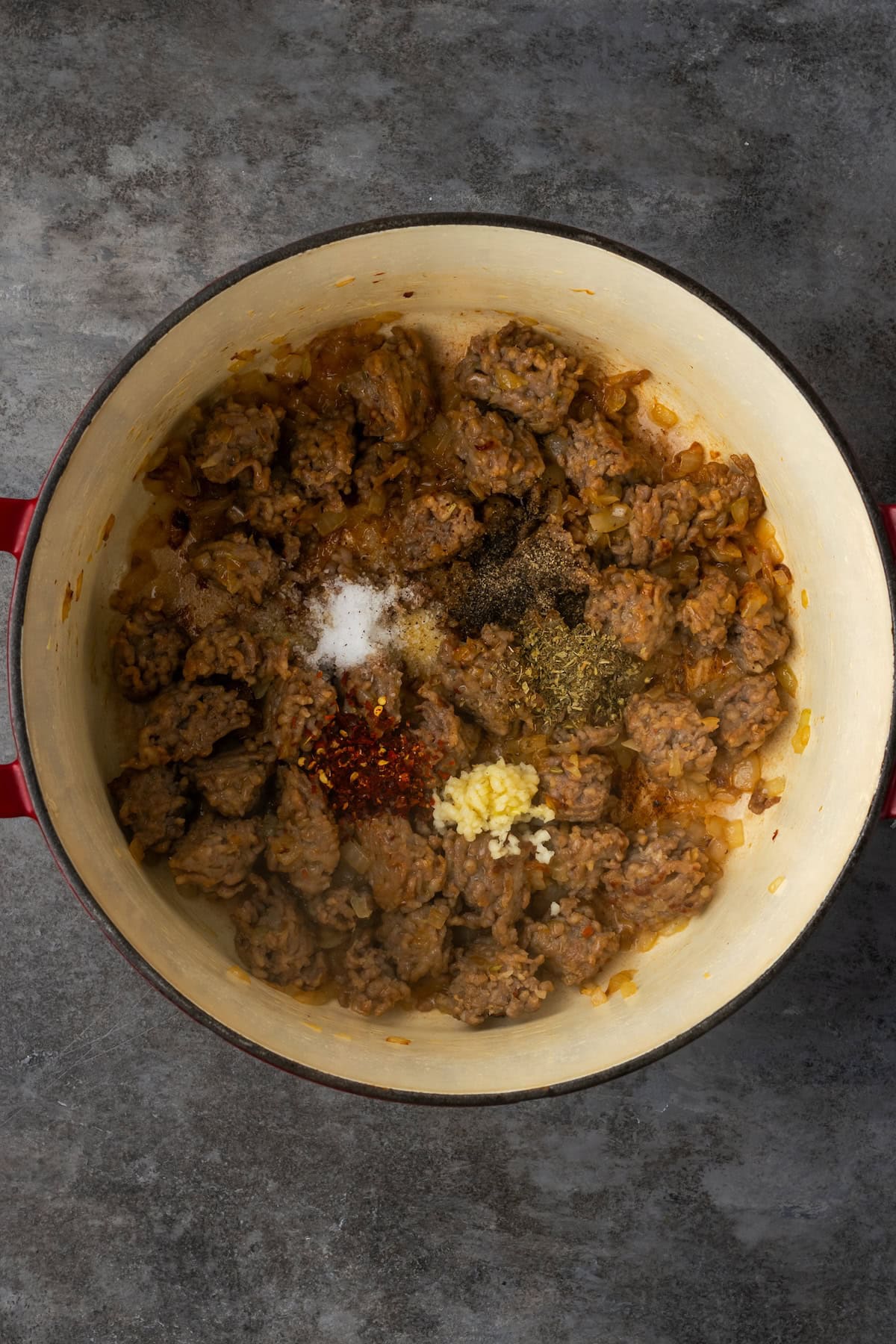 Browned sausage and onions in a Dutch oven.