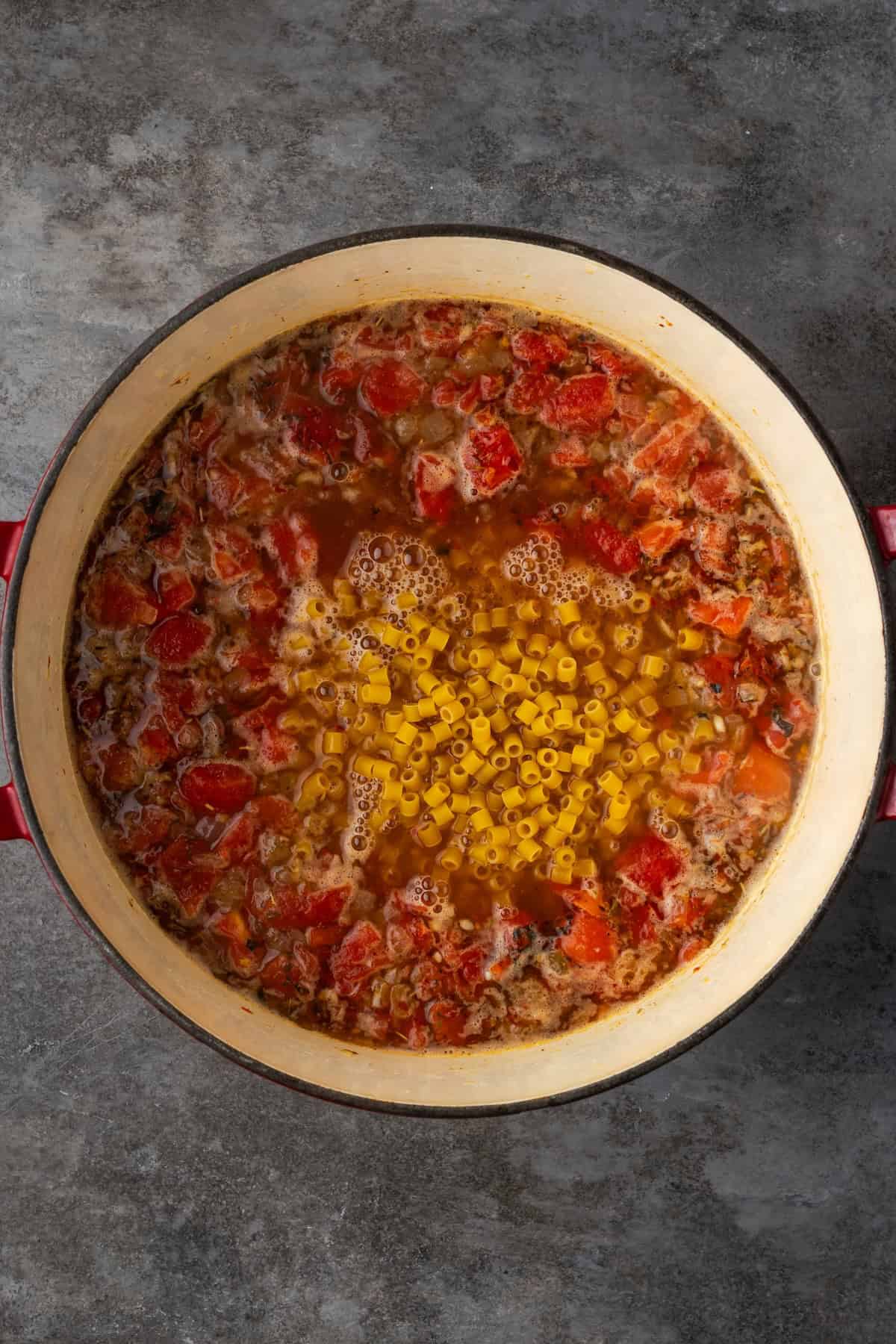 Ditalini pasta added to a pot of Italian sausage soup.