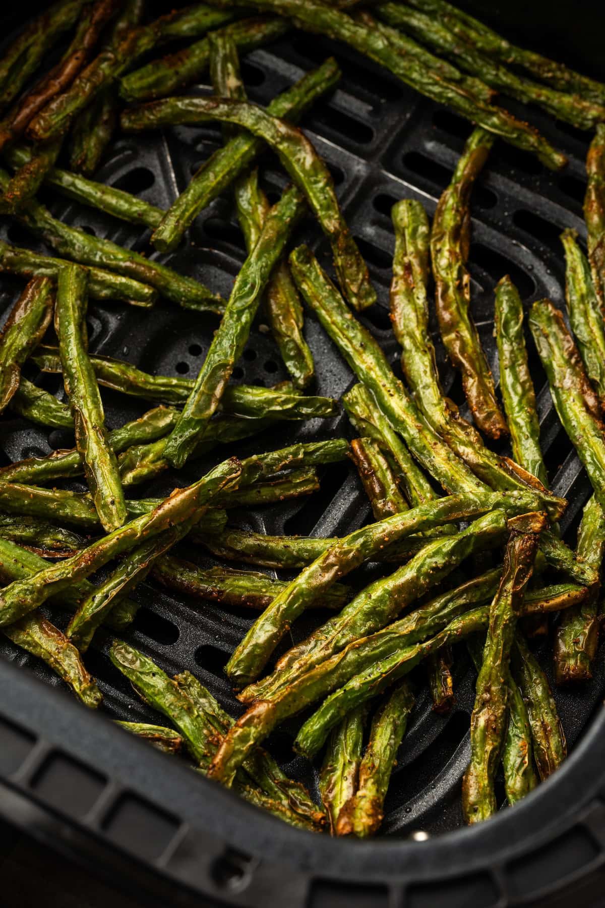 Crispy roasted green beans inside the air fryer.
