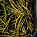 Overhead view of crispy green beans inside the air fryer.