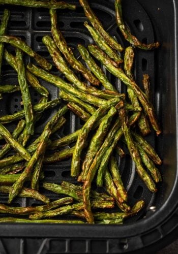 Overhead view of crispy green beans inside the air fryer.