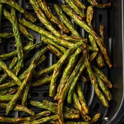 Overhead view of crispy green beans inside the air fryer.