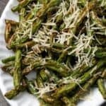 Air fryer green beans topped with parmesan cheese on a large platter.