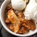 Overhead view of a serving of apple brown betty in a bowl topped with scoops of ice cream.