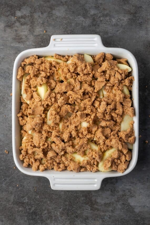 Crumble layered with apple slices in a baking dish.