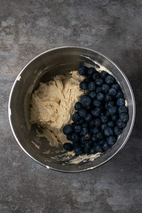 Blueberries added to cake batter in a bowl.