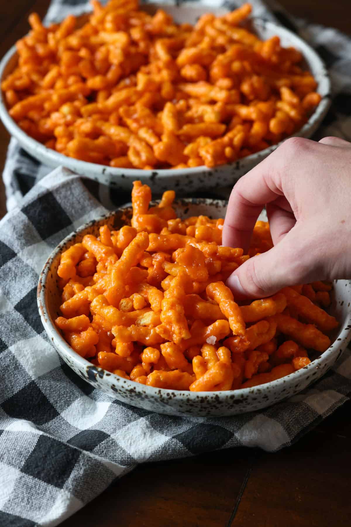 A bowl of caramel Cheetos with a hand taking some