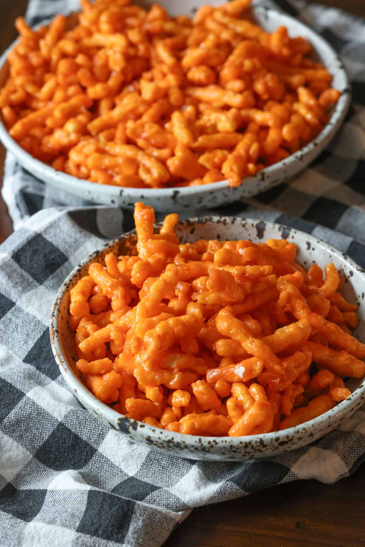 Two bowls of crunchy Cheetos coated in a sweet caramel sauce and baked