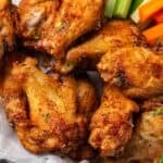 Close up of air fryer chicken wings in a serving basket with crudités and a side of ranch dressing.
