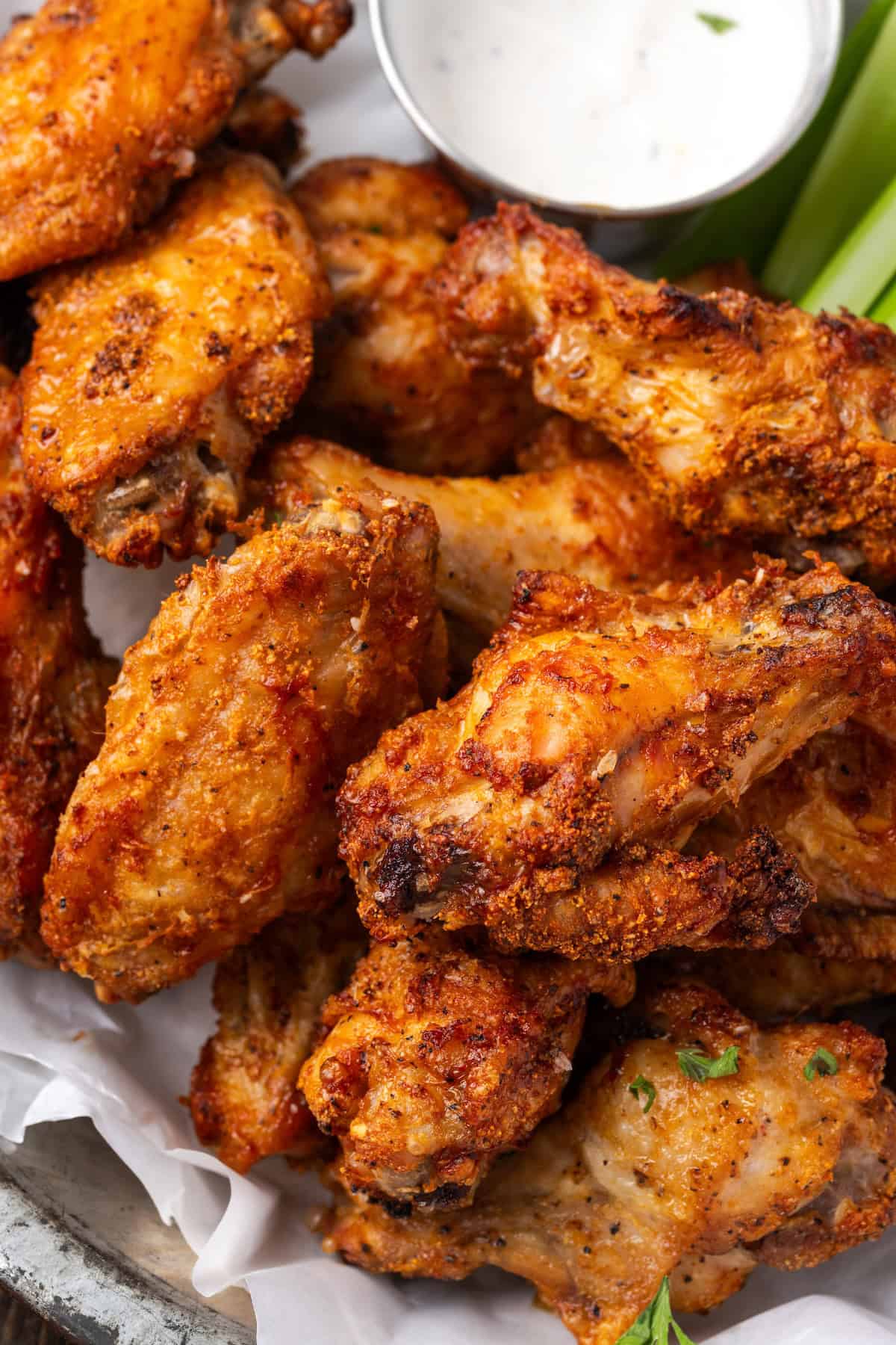 Close up of air fryer chicken wings in a serving basket with a side of ranch dressing.