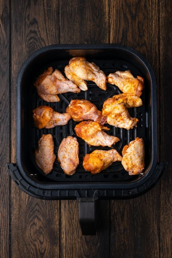 Seasoned chicken wings arranged in a single layer inside the air fryer.